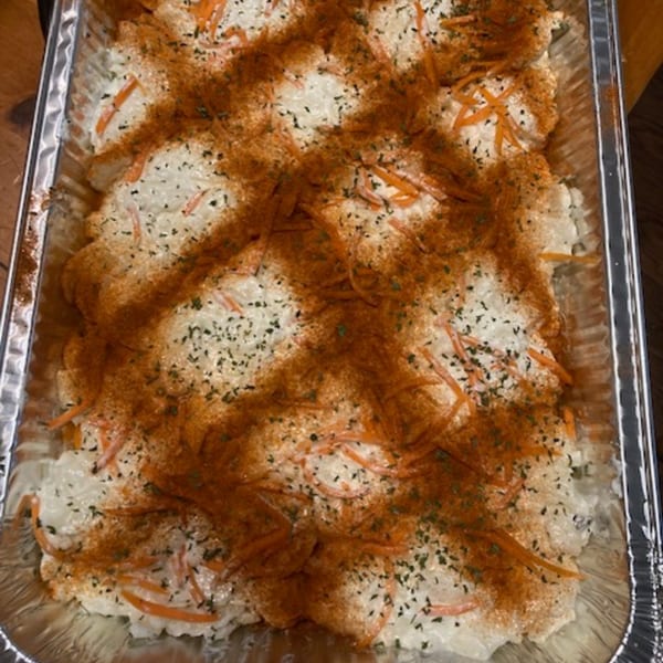 Creamy mac and cheese with shredded carrots, paprika, and herbs in a foil pan.