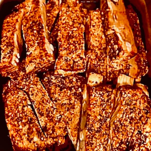 Close-up of FATBOYSBBQ's ribs, heavily seasoned and glistening with sauce.