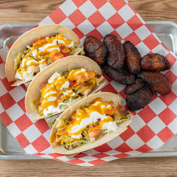 Three FATBOYSBBQ tacos with cheese, sour cream, and lettuce, served with fried plantains.