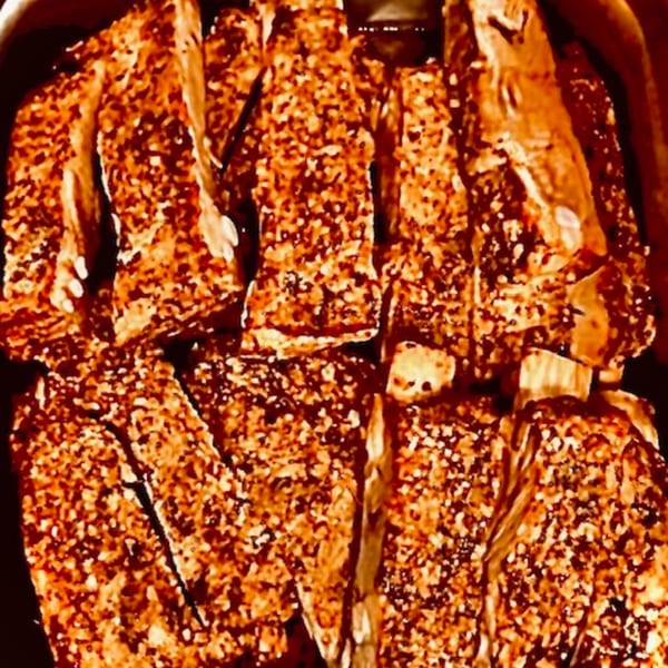 Close-up of FATBOYSBBQ ribs, heavily seasoned with a dry rub, ready to be served.