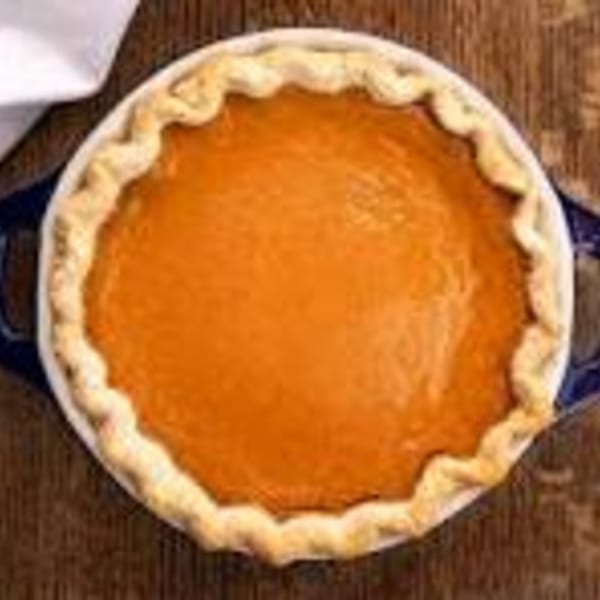 A whole, freshly baked pumpkin pie with a golden-brown crust in a white and blue dish.